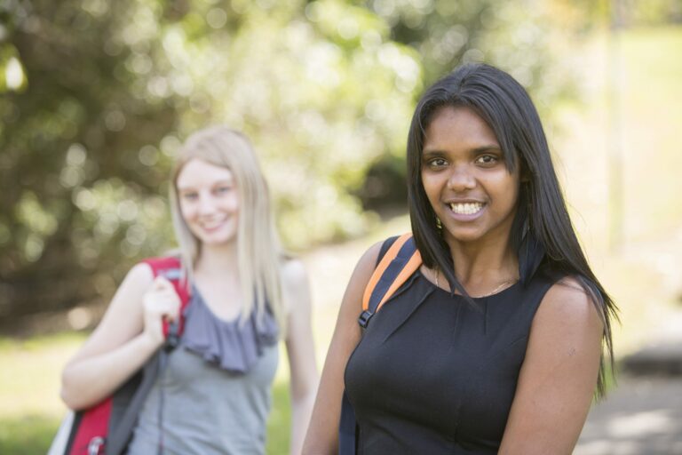 Two females smiling, wearing backpacks